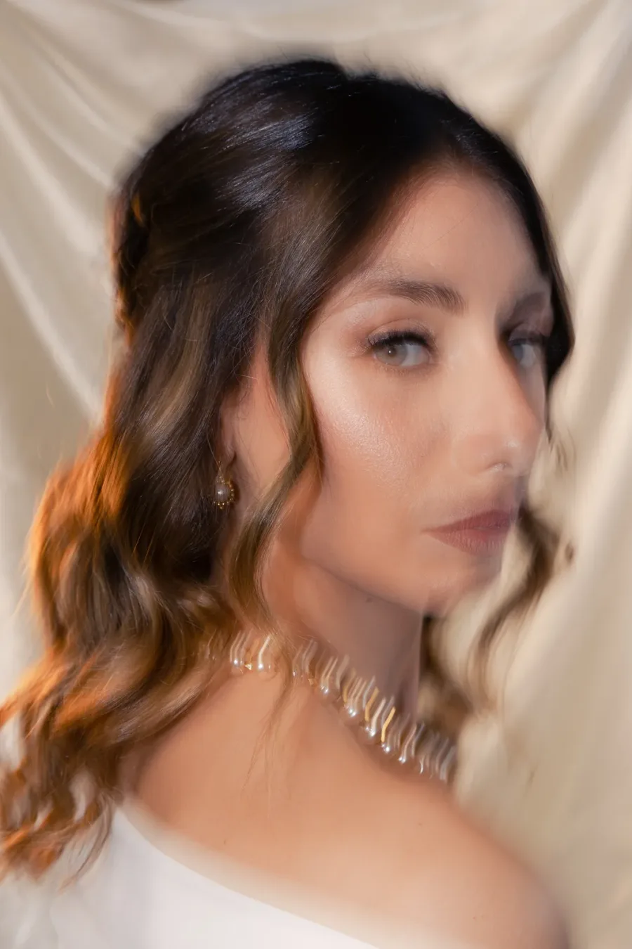 Brown wavy hair in soft motion, silver necklace