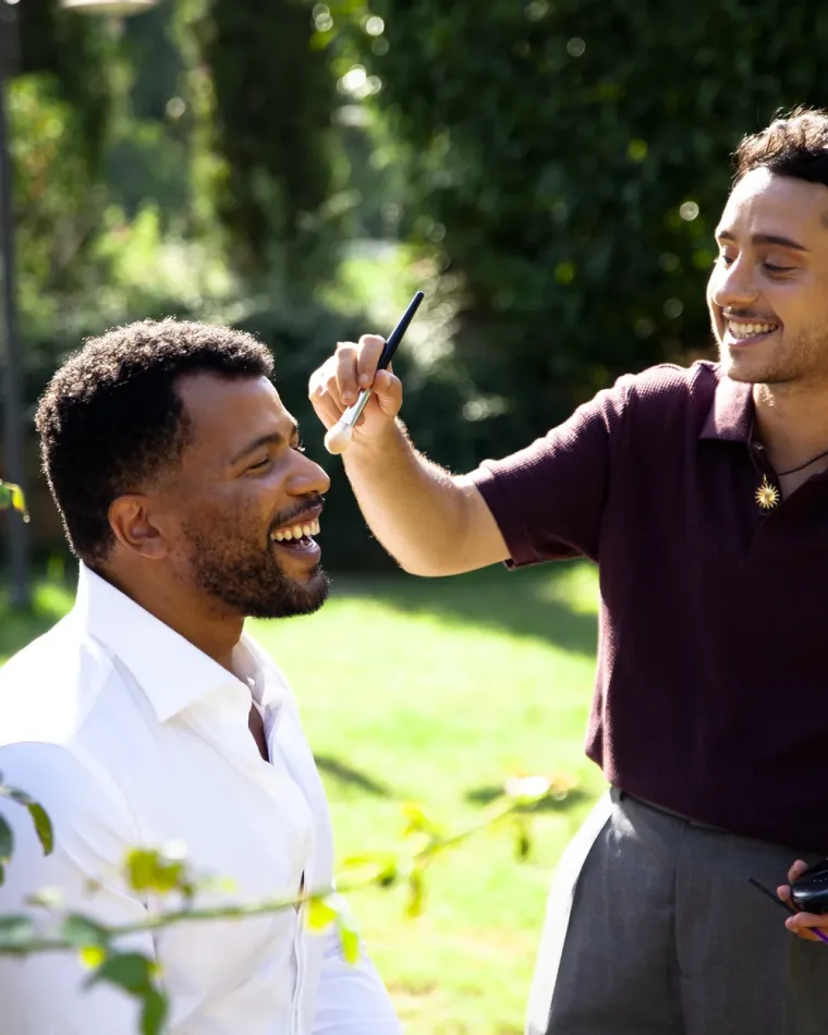 Un artista di Beauty Dream Team sistema il viso di un cliente con la barba, in giardino